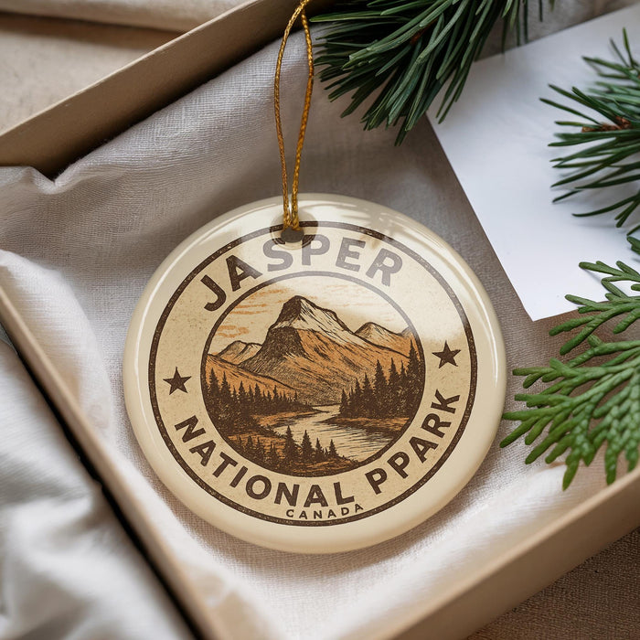 A round ornament with the text "JASPER NATIONAL PARK CANADA" printed on it, surrounded by pine branches and a white paper.