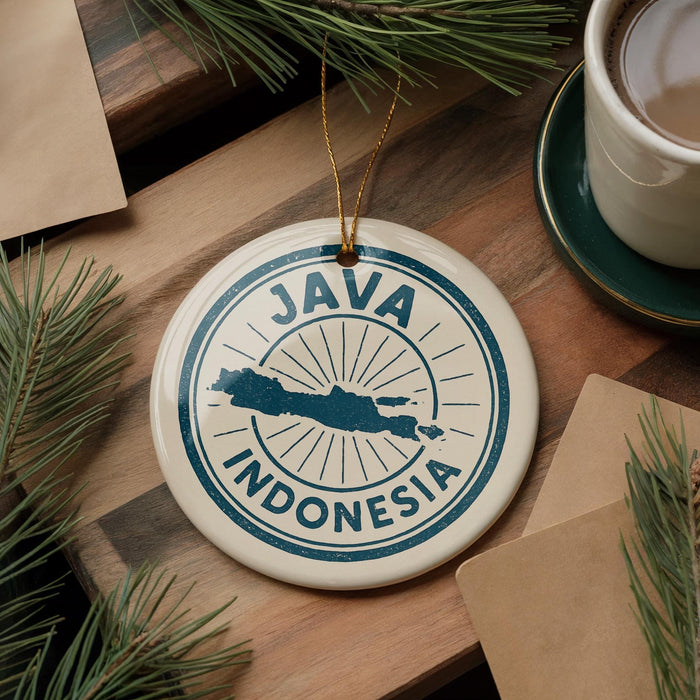 A circular ornament with the text "JAVA INDONESIA" printed on it, surrounded by pine branches and a cup of coffee on a wooden surface.
