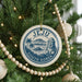 A Christmas tree decorated with ornaments, including a circular ornament with the text "Jeju South Korea" and a palm tree illustration.