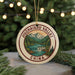 A round ornament with a mountain landscape and waterfall design, featuring the text "JIZUHAI GOU VALLEY CHINA" on it.