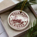 A circular ornament with the text "KALAMAZOO, MICHIGAN" printed on it, surrounded by pine branches.
