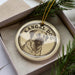 A circular ornament with a dog image and the text "KANGAL DOG" on it, placed in a box with pine branches.