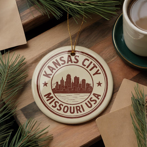 A circular ornament with the text "KANSAS CITY MISSOURI USA" printed on it, surrounded by pine branches and a cup of coffee on a wooden surface.