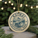 A circular ornament with the text "KATMAI NATIONAL PARK USA" and an illustration of a bear walking on a path, surrounded by pine trees and mountains, is hanging from a string.