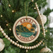 A circular ornament on a Christmas tree with the text "HAWAII US" and a tropical landscape design.