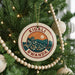 A circular ornament on a Christmas tree, featuring a cityscape and the text "KIGALI RWANDA".