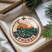 A decorative ornament with the text "KIGALI RWANDA" and an illustration of a cityscape with mountains, hanging from a string.
