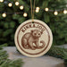 A circular ornament featuring a drawing of a kinkajou, a type of primate, with the text "KINKAJOU" prominently displayed.