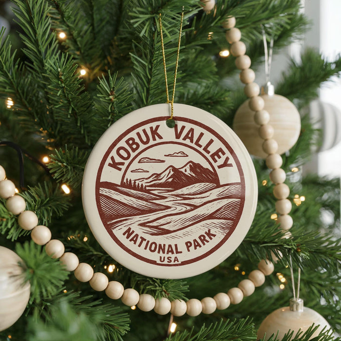 A Christmas tree decorated with ornaments, including a circular ornament with the text "KOBUK VALLEY NATIONAL PARK USA" printed on it.