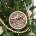 A Christmas tree decorated with ornaments, including a circular ornament with the text "KOBUK VALLEY NATIONAL PARK USA" printed on it.