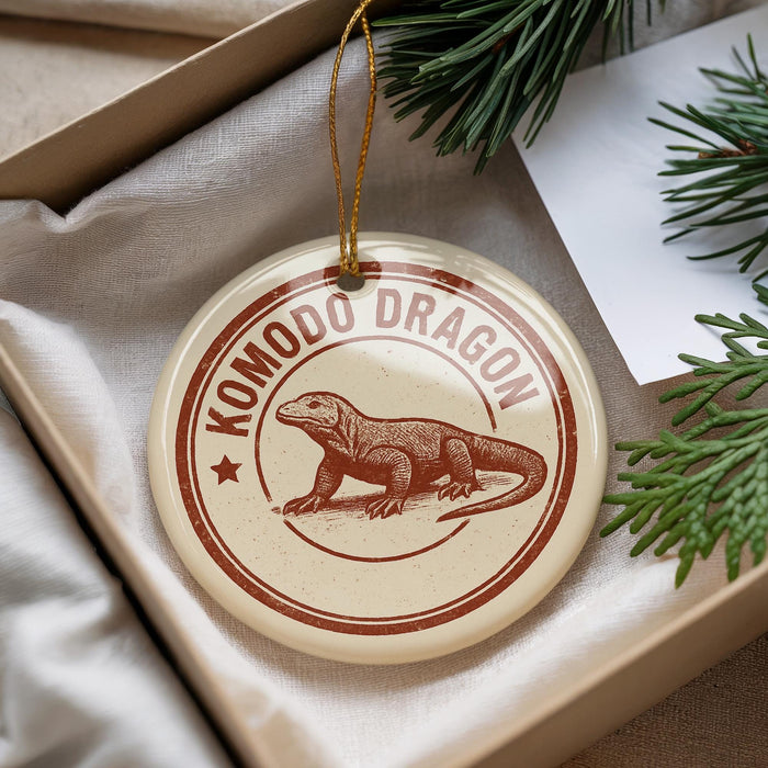 A decorative ornament featuring a komodo dragon, a type of lizard, is displayed in a box with pine branches.