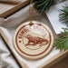 A decorative ornament featuring a komodo dragon, a type of lizard, is displayed in a box with pine branches.