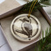 A ceramic ornament in the shape of a bird, specifically a kookaburra, is displayed in a box with pine branches.