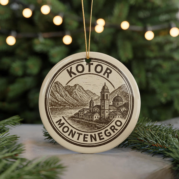 A circular ornament with the text "KOTOR MONTENEGRO" and an illustration of a mountain landscape, hanging from a string.
