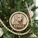 A Christmas tree decorated with ornaments, including a circular ornament with a dog's face and the name "KUVASZ" printed on it.