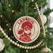 A Christmas tree decorated with ornaments, including a circular ornament featuring a character from the anime series Ladybug.