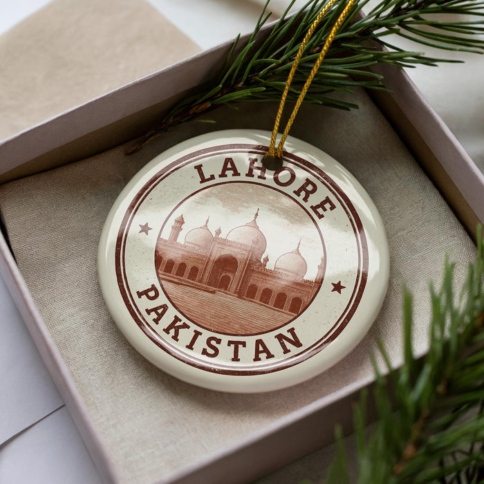 A circular ornament with the text "LAHORE PAKISTAN" and an image of a mosque, placed on a box with pine branches.