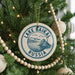 A circular ornament on a Christmas tree, featuring the text "LAKE BAIKAL RUSSIA" and an illustration of a lake and mountains.