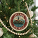 A circular ornament on a Christmas tree, featuring a picture of Lake Bled in Slovenia.