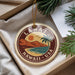A circular ornament with a tropical beach scene and palm trees, featuring the text "LÁNAI I HAWAII USA" on it.