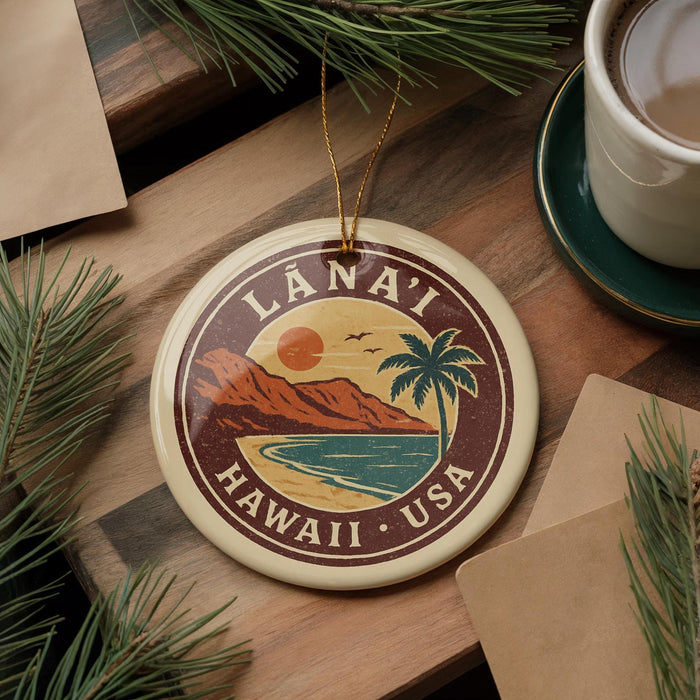 A circular ornament with the text "LÁNAI HAWAII - USA" and a tropical landscape design, hanging on a wooden surface surrounded by pine branches and a cup of coffee.