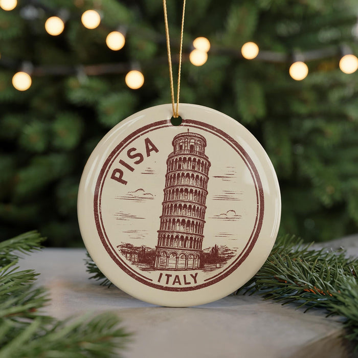 A circular ornament featuring the Leaning Tower of Pisa, a famous landmark in Italy, surrounded by Christmas lights and greenery.