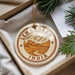 A round ornament with the text "LEH LADAKH INDIA" printed on it, surrounded by a border and a small illustration of a mountain and a village.