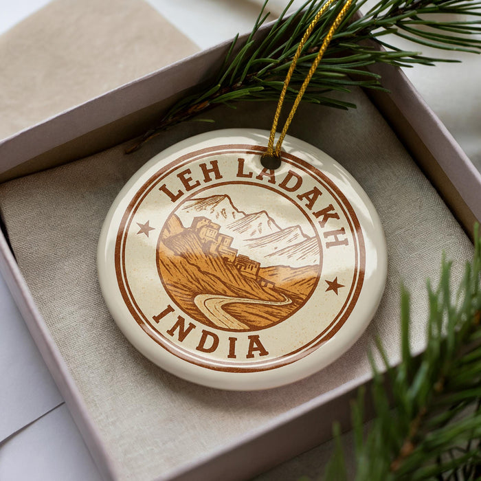 A circular ornament with the text "LEH LADAKH INDIA" printed on it, surrounded by a border and a mountain illustration.