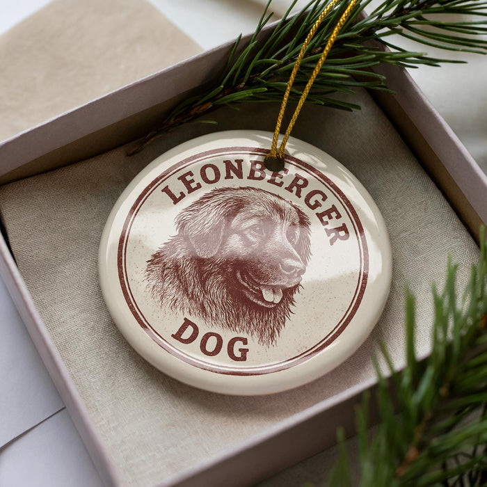 A circular ornament with a dog's head and the text "LEONBERGER DOG" printed on it, placed inside a box with pine branches.