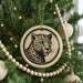 A Christmas tree decorated with ornaments, including a leopard print ornament hanging from the tree.