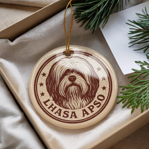 A circular ornament with a brown and white design featuring a dog's face and the text "LHASA APSO" is displayed in a box with pine branches.