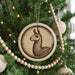 A Christmas tree decorated with ornaments, including a circular ornament featuring a llama illustration.