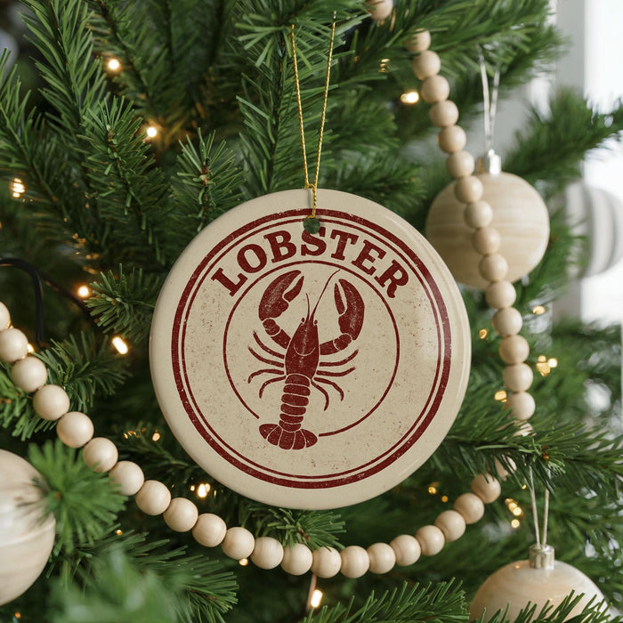 A Christmas tree decorated with a round ornament featuring a lobster design, surrounded by beaded ornaments and twinkling lights.