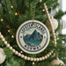 A Christmas tree decorated with ornaments, including a circular ornament with the text "Lofoten Islands Norway" and a mountain landscape.