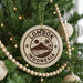 A Christmas tree decorated with ornaments, including a circular ornament with the text "LOMBOK INDONESIA" and a palm tree design.