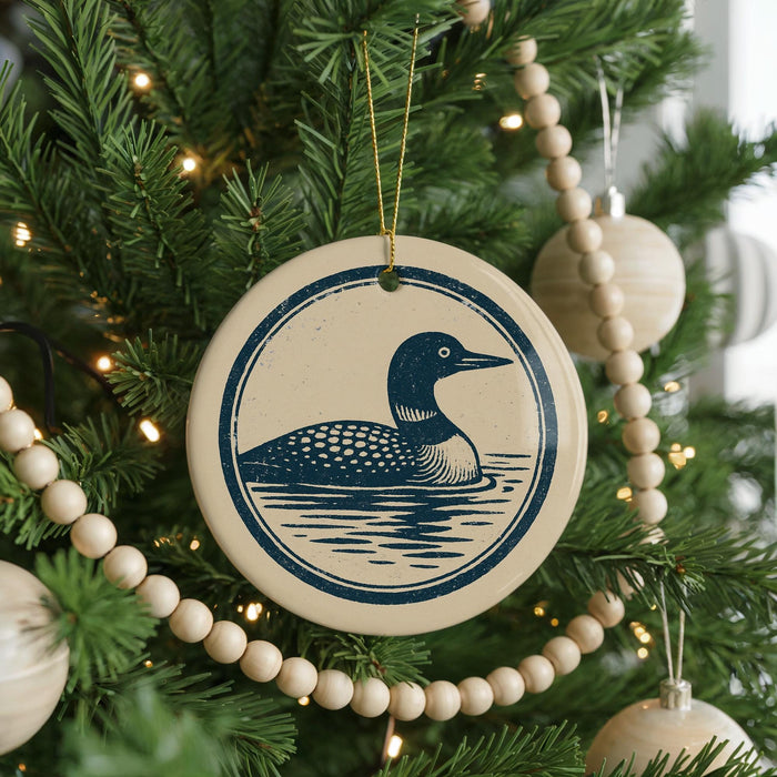 A Christmas tree decorated with ornaments, including a circular ornament featuring a blue duck swimming in a body of water.