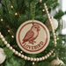 A Christmas tree decorated with ornaments, including a round ornament with a bird image and the word "LOVEBIRD" written on it.