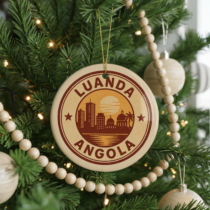 A Christmas tree decorated with ornaments, including a circular ornament with the text "LUANDA ANGOLA" and a cityscape design.