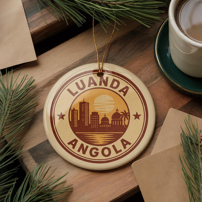 A circular ornament with the text "LUANDA ANGOLA" and a city skyline design, hanging on a wooden surface.