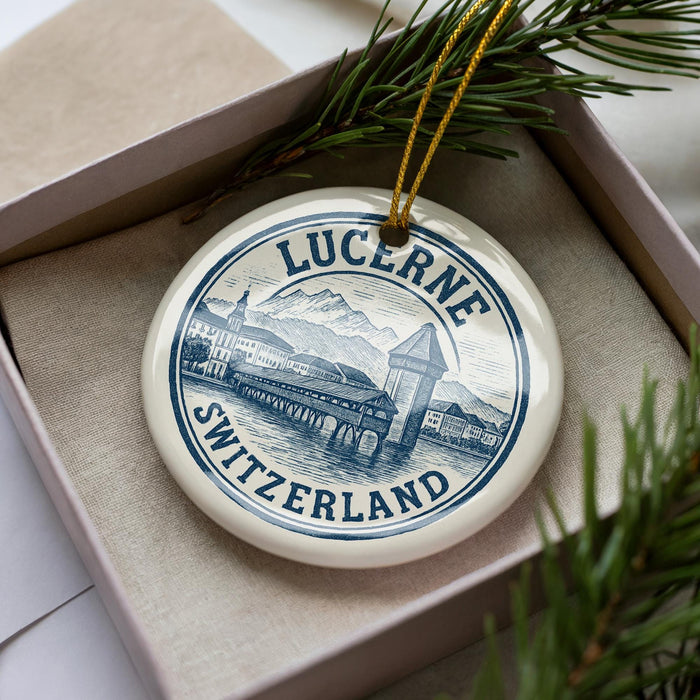 A decorative ornament in a box, featuring a circular design with a mountain landscape and Swiss text.