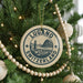 A Christmas tree decorated with ornaments, including a circular ornament with the text "LUGANO SWITZERLAND" and a mountain illustration.