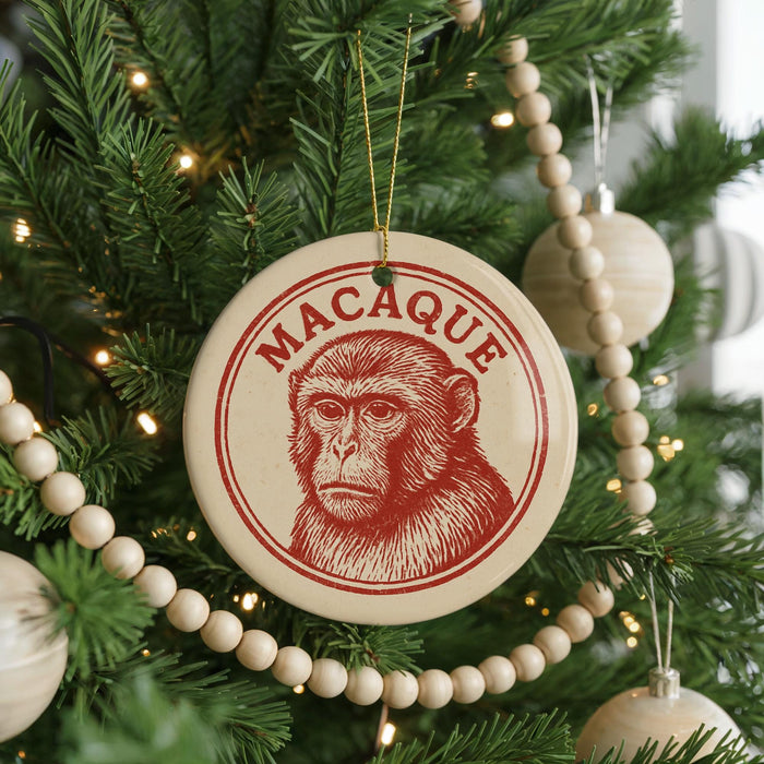 A Christmas tree decorated with ornaments, including a circular ornament with a monkey image and the word "MACAQUE" written on it.