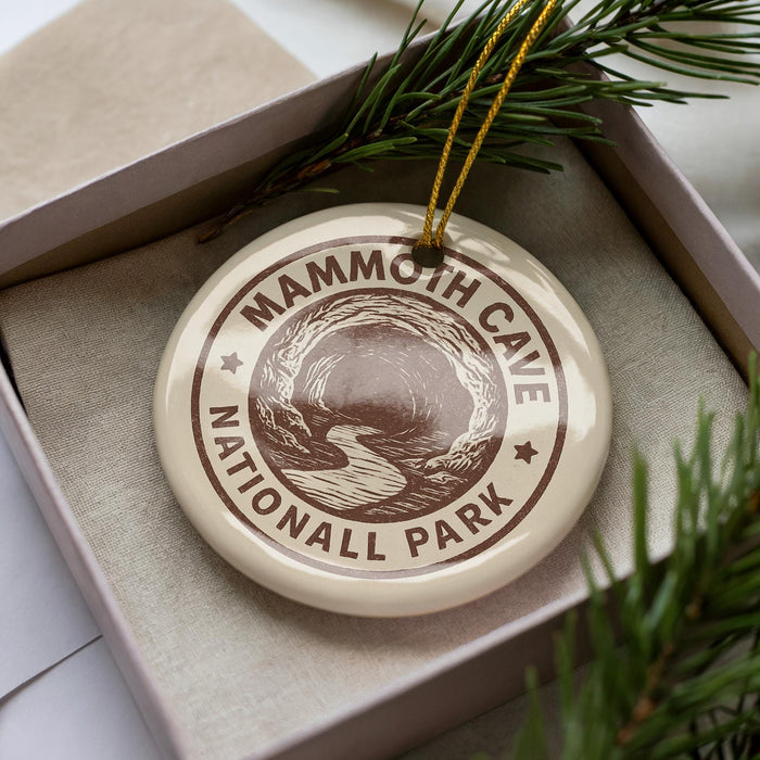 A decorative ornament in a box, featuring the text "MAMMOTH CAVE NATIONALL PARK" and an illustration of a cave surrounded by trees.
