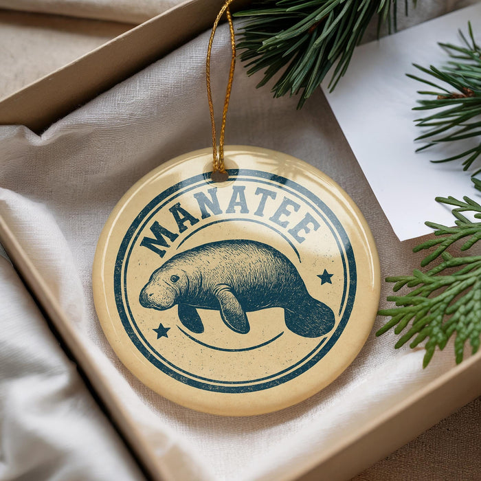 A circular ornament with a manatee illustration and the word "MANATEE" printed on it, hanging from a string.
