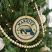 A Christmas tree decorated with ornaments, including a circular ornament with a manatee design and the word "MANATEE" written on it.