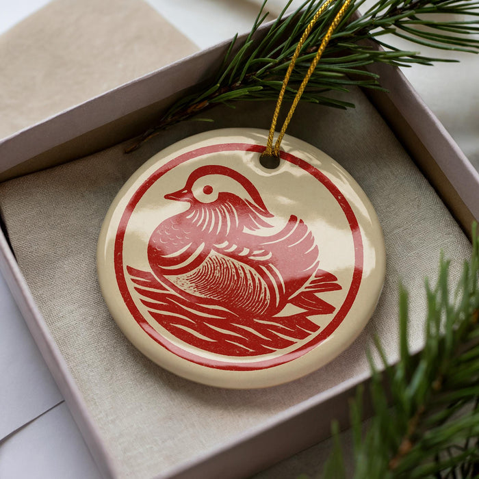 A decorative ornament in a box, featuring a red bird design.