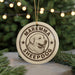 A circular ornament with the text "MAREMMA SHEEPDOG" and a graphic of a dog's head is displayed in front of a Christmas tree with twinkling lights.