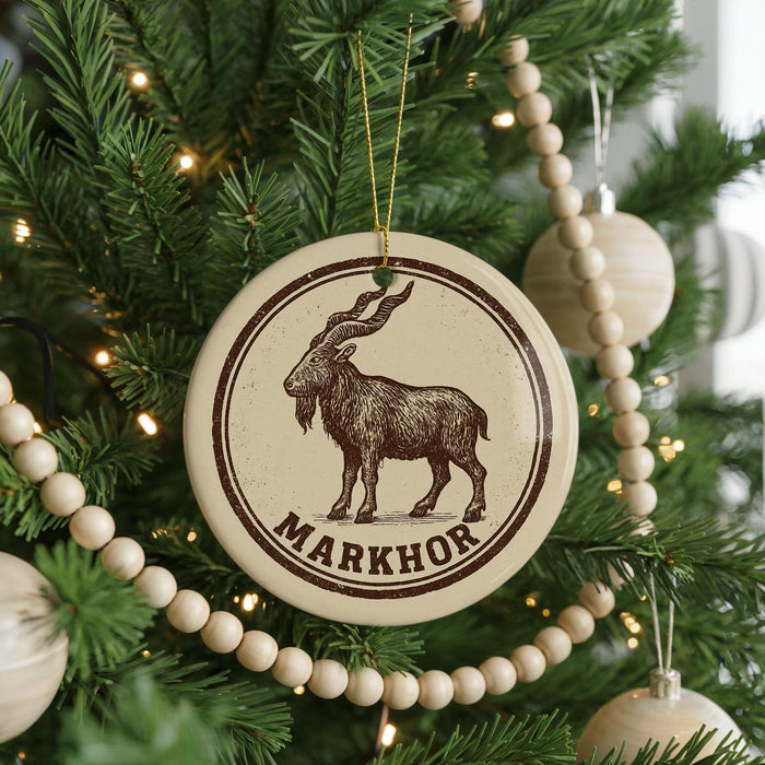 A Christmas tree decorated with ornaments, including a circular ornament with a goat illustration and the word "MARKHOR" written on it.