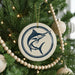 A Christmas tree decorated with ornaments, including a round ornament with a blue and white design featuring a fish.