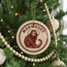 A round ornament with a monkey on it, hanging on a Christmas tree.